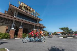 two people riding a bike in front of a store at Tok Aman Bali Beach Resort @ Beachfront in Kampong Ayer Tawar