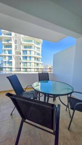 a glass table and chairs on top of a building at Sunset Poolside Apartment with Pool facility in Larnaca