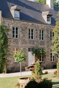a large stone house with a white garage at Domaine du tertre ychot in Dol-de-Bretagne