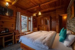 a bedroom with a bed in a log cabin at Ishan Log Huts-A boutique home stay in Banjār