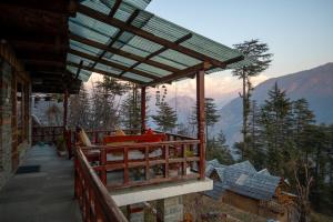a balcony of a house with a view of the mountains at Ishan Log Huts-A boutique home stay in Banjār +86 photos