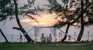 two people sitting at a table in front of the ocean at Anantara Mai Khao Phuket Villas in Mai Khao Beach +208 photos