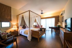 a bedroom with a canopy bed and a living room at Tok Aman Bali Beach Resort @ Beachfront in Kampong Ayer Tawar