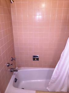 y baño con bañera y azulejos rosados. en Sharon Motel, en Wells
