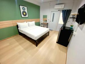 a bedroom with a white bed and a green wall at 9TY hotel (ninety hotel) in Bangkok