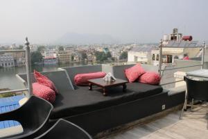 a balcony with a bench with pillows and a table at Hotel Pratap Bhawan in Udaipur