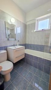 a bathroom with a toilet and a sink and a tub at Sunset Poolside Apartment with Pool facility in Larnaca