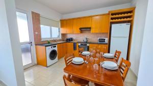 a kitchen with a wooden table with chairs and a dining room at Sunset Poolside Apartment with Pool facility in Larnaca