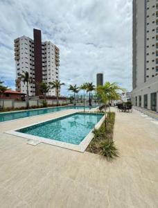 a large swimming pool with palm trees and buildings at Apartamento Cabedelo João Pessoa in Cabedelo