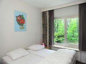 two beds in a room with a window at Quaint Villa in Doornspijk with Swimming Pool in Doornspijk