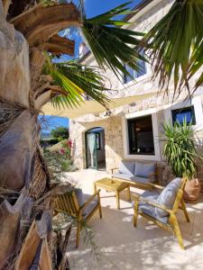 a patio with chairs and a table and a tv at Villa Šjora - ''Autentic Dalmatian Stone Villa with Private Garden & BBQ'' in Vrboska +32 photos