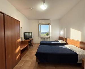 a room with two beds and a desk and a television at Hotel Serena in Riolo Terme