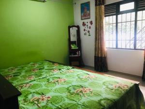 a green bedroom with a bed with a green comforter at Shanu home stay in Beliatta