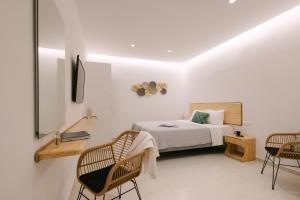 a bedroom with a bed and two chairs at Anemos Hotel & Apartments in Ornos +122 photos