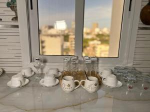 a white table with glasses and cups and a window at FASA RESIDENCE Dakar CHAMBRE TERANGA in Dakar