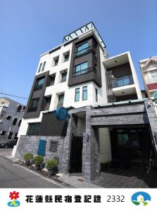 a tall white building with black balconies on a street at 52 travelers home (with elevator) in Hualien City