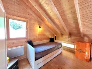 a room with a bed in a wooden cabin at Chalet Cocoon 6p avec Spa privé in Rochesson