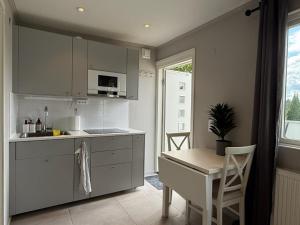 a kitchen with white cabinets and a table and a chair at Siam Homestay 2 in Mölndal