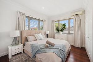 a white bedroom with a large bed with two windows at Bedford Pool Oasis - Comfort near CBD & Airport in Perth