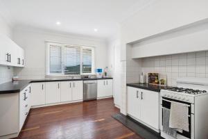 a kitchen with white cabinets and a stove top oven at Bedford Pool Oasis - Comfort near CBD & Airport in Perth +20 photos