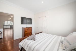 a white bedroom with a bed and a dresser at Bedford Pool Oasis - Comfort near CBD & Airport in Perth