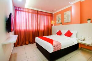 a bedroom with a bed with red curtains and a television at OYO 761 City Hotel in Kuala Lumpur