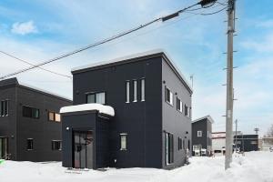 a black building in the snow next to a pole at 雪舞-YukiMai in Kutchan