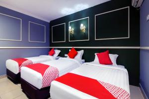a room with three beds with red and white sheets at OYO 761 City Hotel in Kuala Lumpur
