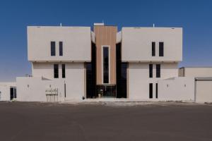 a white building with black windows and a parking lot at المحروسة للشقق المفروشة Mahrousa Apartment in Medina