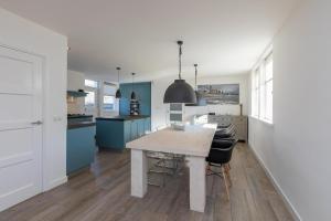 a kitchen with a wooden table and blue cabinets at Welcome in - Familiehuis met ruim terras en speelweide I Oostkapelseweg 32, Serooskerke 'Ooievaar' in Serooskerke