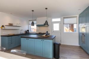 a kitchen with blue cabinets and a black counter top at Welcome in - Familiehuis met ruim terras en speelweide I Oostkapelseweg 32, Serooskerke 'Ooievaar' in Serooskerke