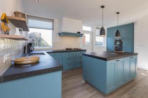 a kitchen with blue cabinets and a counter top at Welcome in - Familiehuis met ruim terras en speelweide I Oostkapelseweg 32, Serooskerke 'Ooievaar' in Serooskerke