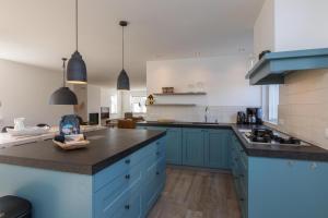 a kitchen with blue cabinets and black counter tops at Welcome in - Familiehuis met ruim terras en speelweide I Oostkapelseweg 32, Serooskerke 'Ooievaar' in Serooskerke +43 photos