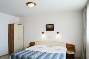 a bedroom with a bed with a blue and white sheets at Hotel Oasis - Beach Access in Balchik