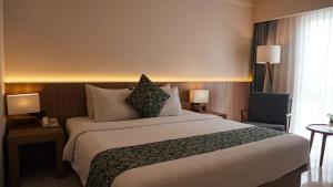 a hotel room with a large bed and a chair at Tusita Boutique Hotel in Kuta