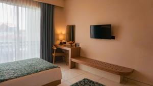 a hotel room with a bed and a desk and a television at Tusita Boutique Hotel in Kuta