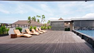 a row of lounge chairs on a deck next to a pool at Tusita Boutique Hotel in Kuta