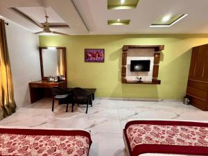 a room with a bedroom with a table and a tv at Sanskar Resort in Pānāgar