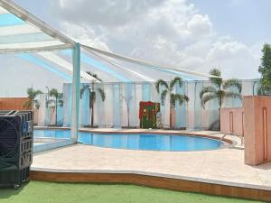 a building with a swimming pool and palm trees at Sanskar Resort in Pānāgar
