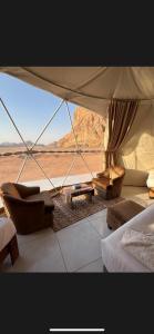 a bedroom with a bed and a couch and a view of the desert at Rum Four Seasons luxury Camp & Jeep Tours in Wadi Rum