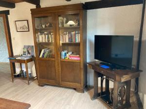 a living room with a tv and a book shelf at LA TONTON in Desseling