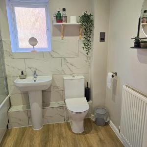 a bathroom with a toilet and a sink and a window at Welcome Home in Royston +7 photos
