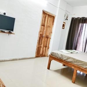a room with a bed and a tv and a door at Dapolihideaway in Dapoli