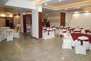 a room with white tables and chairs and a man standing in the background at Hotel Nilax in Jaipur
