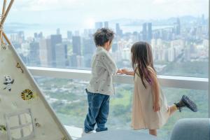 a boy and a girl standing on the edge of a window at Mandarin Oriental, Shenzhen in Shenzhen
