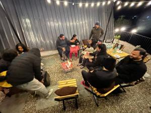 a group of people sitting around a fire in a room at The Alchemist Rishikesh in Birbhaddar