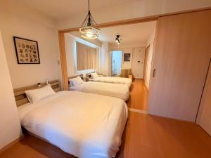 a bedroom with two beds and a window at ura アオトハル2 in Okayama
