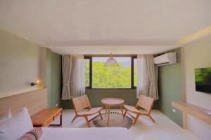 a bedroom with a bed and two chairs and a table at HOTEL NUU CHIANG MAI in Chiang Mai