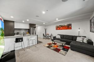 a living room with a black couch and a kitchen at Stylish Central Braddon 1 Bed, Pool, Gym, Parking in Canberra