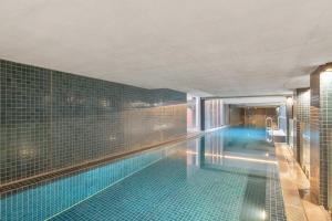 a swimming pool in a building with blue tiles at Stylish Central Braddon 1 Bed, Pool, Gym, Parking in Canberra